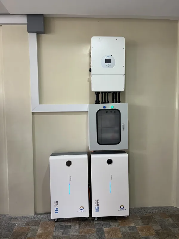 Hybrid inverter above a glass-front protection enclosure and two battery cabinets on a beige wall