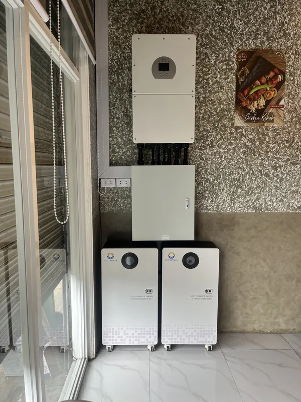 Hybrid inverter, protection enclosure and two battery cabinets beside a glass door